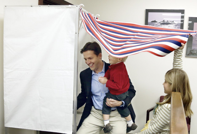 Republican Senate candidate Ben Sasse enters the voting booth with his son Breck, as daughter Alexandra holds the curtain open, during early voting in Fremont, Nebraska, Oct. 31, 2014. (AP Photo)