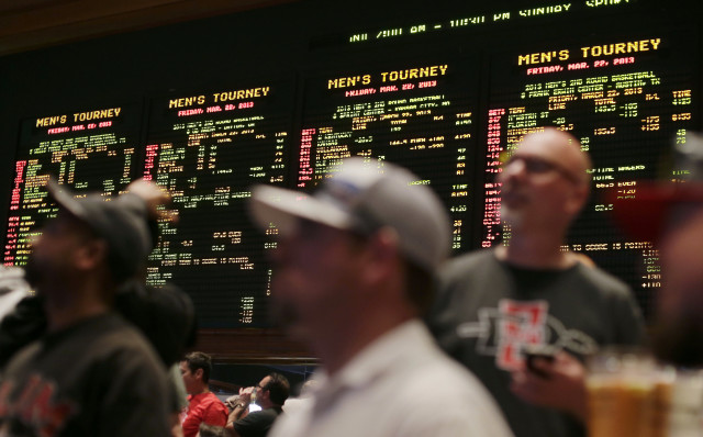 In this March 22, 2013, photo, bettors watch the odds for second-round NCAA tournament games displayed on a board at the Mirage hotel-casino Race & Sports Book in Las Vegas, Nevada. (AP Photo) 