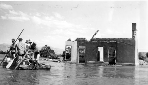 A salvage crew rafts through the town of St. Thomas near the ruins of a building as Lake Mead begins to submerge it in June 1938. (Lake Mead NRA Public Affairs via Flickr)