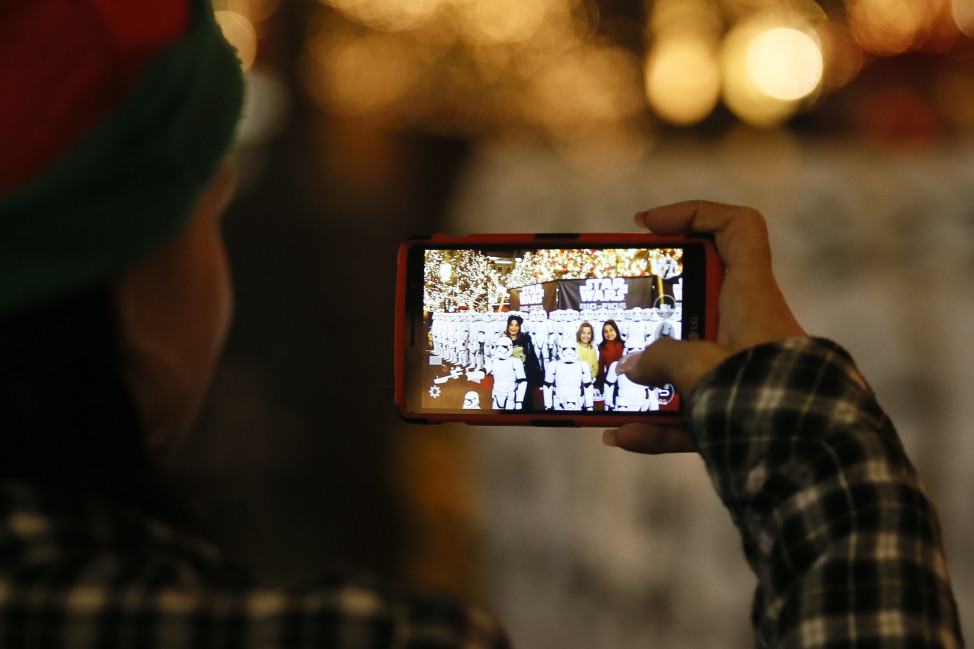 A woman uses a mobile device to take a photograph  Dec. 17, 2015, in Glendale, California. (AP Photo)