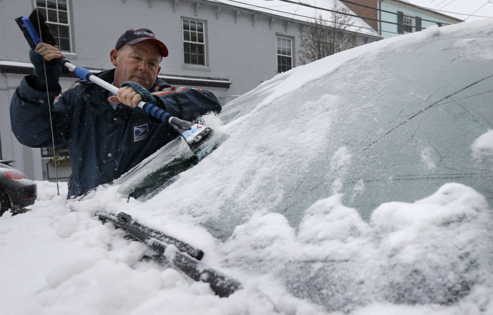 Postal worker Buddy Collins of Eliot, Maine, scrapes ice and snow from his windshield, Dec. 29, 2015, in Portsmouth, New Hampshire. (AP Photo) 