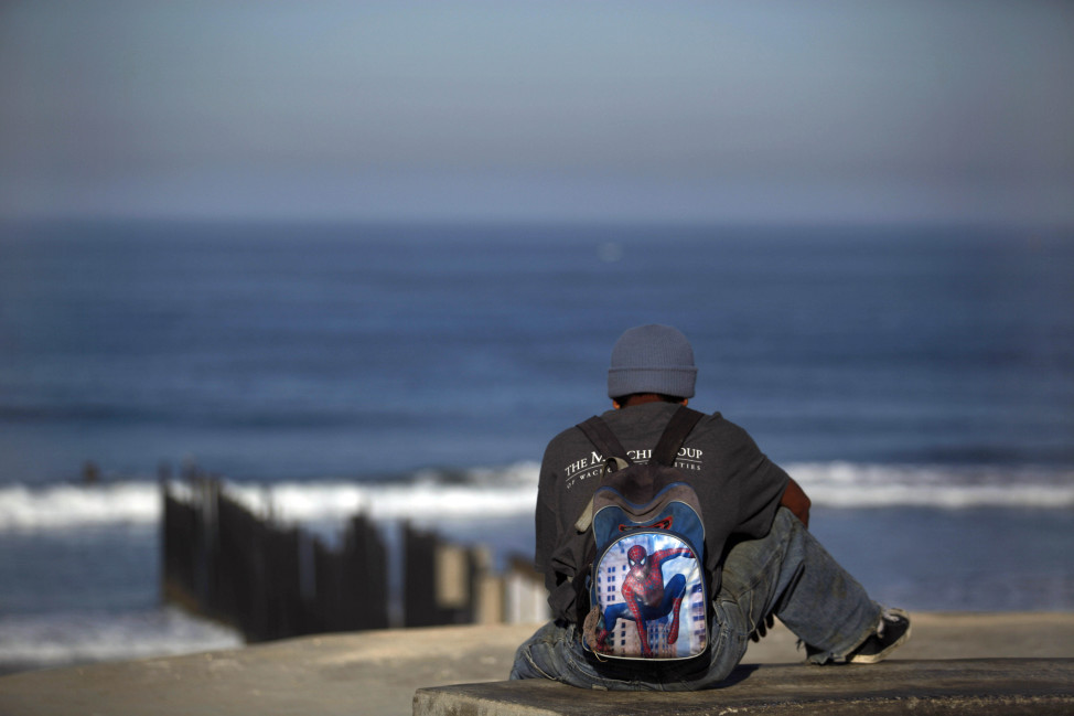 FILE -- A recently deported migrant from Seattle waits for a chance to cross to the U.S. near the US-Mexico border fence in Tijuana. (AP Photo)