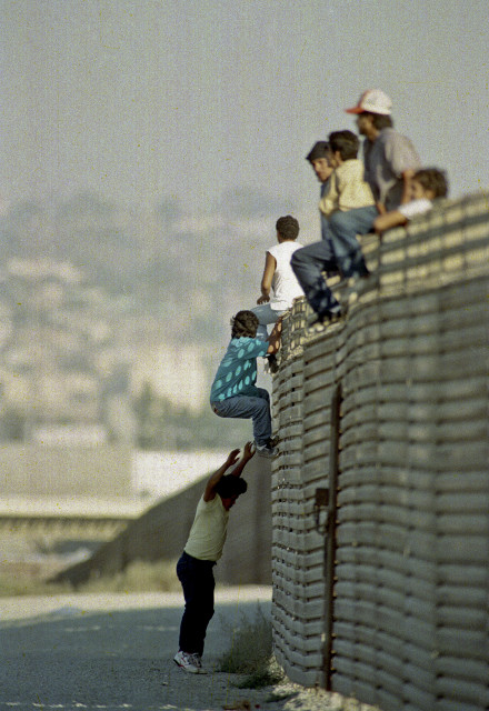 FILE - In this Oct. 14 1991 file photo, a group of illegal Mexican immigrants jump from a border fence to enter the United States, near Tijuana, Mexico. (AP Photo)