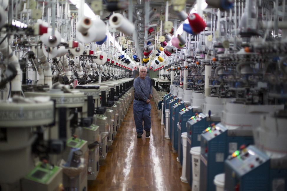 A worker walks between automatic sock knitting machines at Shankel's Hosiery manufacturing facility in Fort Payne, Alabama, Oct. 22, 2015. (Reuters)