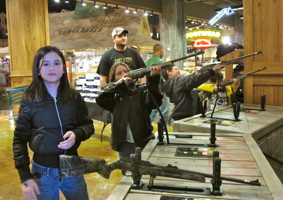 Chris Horsley of Texarkana, Texas, watches his children take aim at the shooting gallery in Bass Pro Shops at the Pyramid, a retail center in Memphis, Tennessee. From left are Jordana, Christa, Corbin and Mason. (C. Guensburg/VOA)   