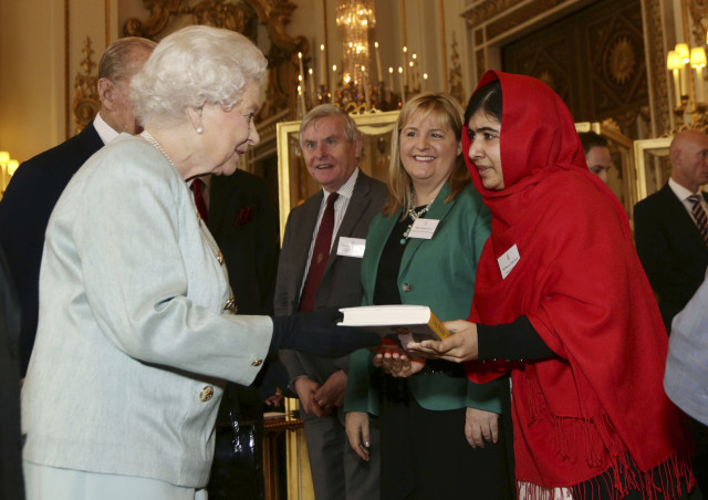 Malala Yousafzai gives a copy of her book to Britain's Queen Elizabeth during a Reception at Buckingham Palace in London