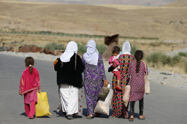 Women and children from the minority Yazidi sect, fleeing the violence in the Iraqi town of Sinjar, walk to a refugee camp after they re-entered Iraq from Syria at the Iraqi-Syrian border crossing in Fishkhabour