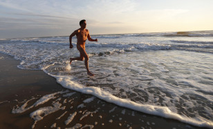 A French naturist jogs on the beach at sunset during his holiday at the Centre Helio-Marin naturist campsite on the Atlantic coast in Montalivet