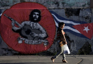 A woman walks past graffiti of revolutionary hero Ernesto "Che" Guevara and a Cuban flag of mexican artistic group Azaro for the 12th Havana Biennial, in Havana