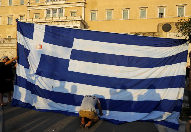 Protester kneels to pay his respect in front of a Greek flag during an anti-austerity rally in Athens