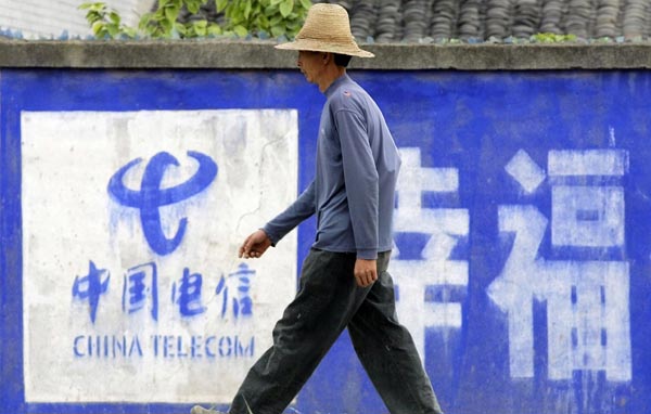A villager walks past a billboard for China Telecom