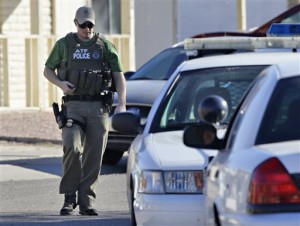 Seorang polisi berjalan di depan rumah Jared Lee Loughner di Tucson, Arizona, Sabtu, 8 Januari 2011 (AP Photo/Matt York).