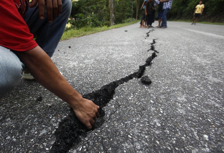 An Indian boy shows a crack of damaged road in Gangtok, India. (AP)