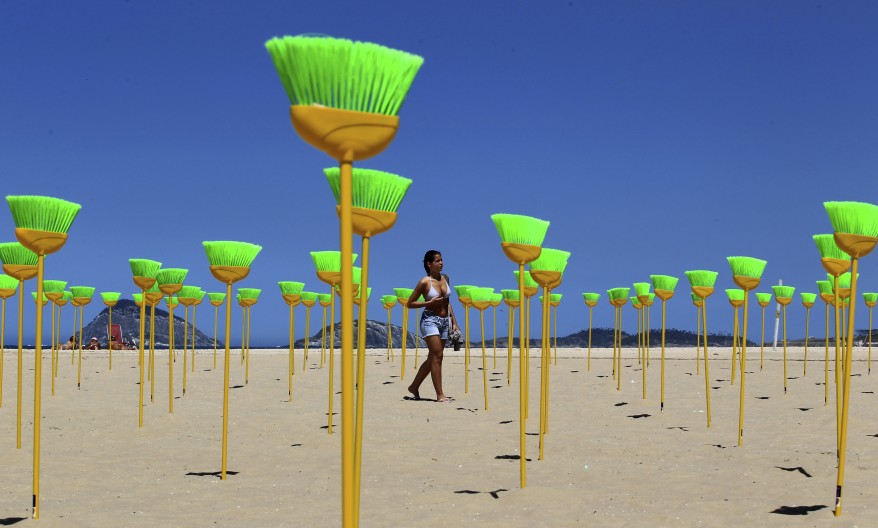 A woman walks near brooms placed at Copacabana beach as a form of protest in Rio de Janeiro. (Reuters)