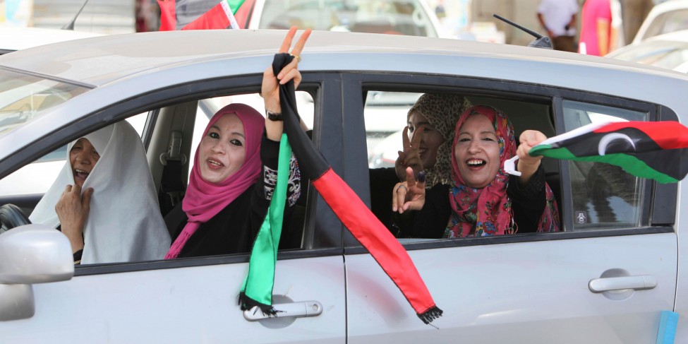 Libyan women celebrate the holding of elections by waving a Libyan flag and flashing the victory sign as they drive in Tripoli, Libya, July 7, 2012. (AP)