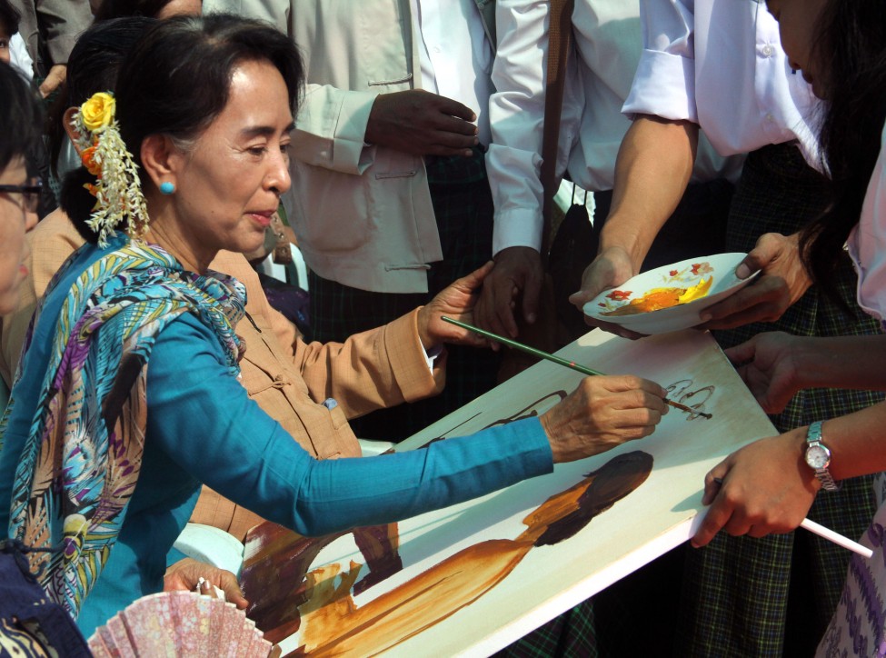 缅甸反对派领袖昂山素姬在她的支持者画的画像上签名。(美联社)