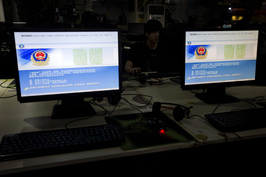 A computer user sits near displays with a message from the Chinese police on the proper use of the internet at an internet cafe in Beijing, China, Monday, Aug. 19, 2013.
