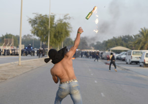 An anti-government protester throws a Molotov cocktail at riot police during clashes after the funeral procession of Ahmed Abdul-Ameer in the village of Sanabis, west of Manama, November 30, 2013.  According to police, Abdul-Ameer died after suffering burns as he tried to set a warehouse on fire during an anti-government protest. Opposition activists said that he died when he tried to burn tires on the road to create road blocks in the village. REUTERS/Stringer 