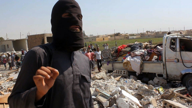 An image grab taken from an AFPTV video on September 16, 2014 shows a jihadist from the Islamic State (IS) group standing on the rubble of houses after a Syrian warplane was reportedly shot down by IS militants over the Syrian town of Raqa. The plane crashed into a house in the Euphrates Valley city, the sole provincial capital entirely out of Syrian government control, causing deaths and injuries on the ground. AFP PHOTO / AFPTV / STR