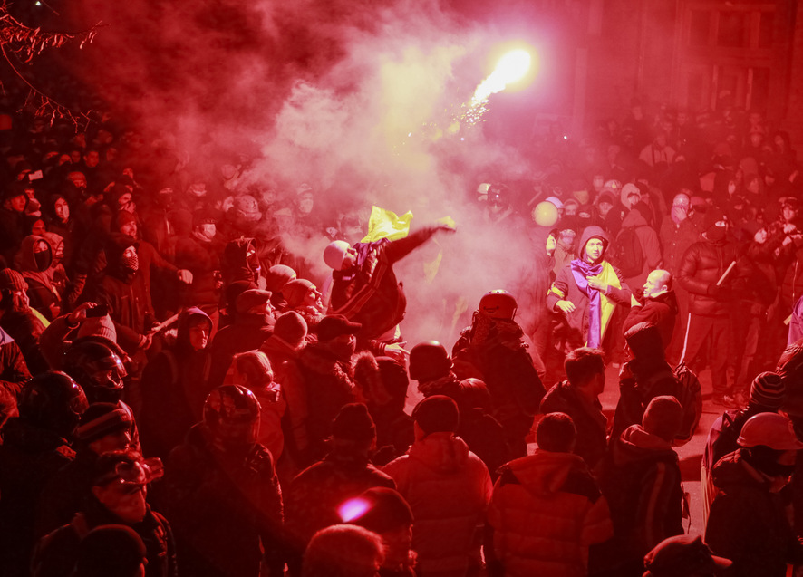 A man throws a flare in the direction of Interior Ministry members during a rally held by supporters of EU integration in Kiev
