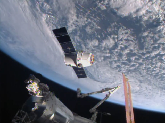 The Dragon spacecraft, seen here in this image from NASA-TV, is about to be grappled by the International Space Station’s robotic arm as it arrives on 4/16/15.  The cargo ship delivered nearly 2,000 kg of food, science experiments, equipment and the first espresso maker in space to the 6 ISS crewmembers (NASA) 