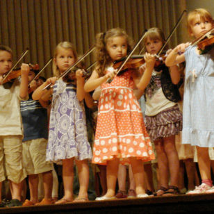 Children playing violin in a group recital at a Suzuki Institute (Stilfehler via Wikimedia Commons)