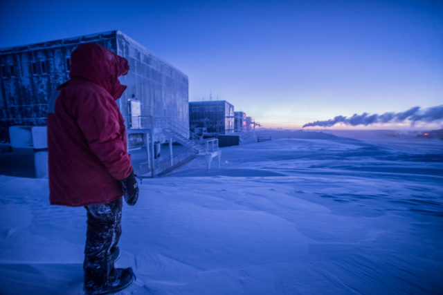 Ten months of blowing snow mean monumental drifts. The author stands on top of one of the larger ones and admires the rugged landscape. (Photo: Hamish Wright)