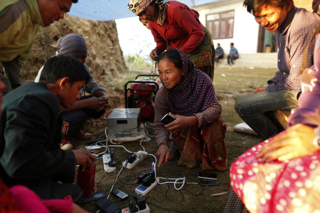 Young villagers charge their mobile phones from a generator in the destroyed village of Paslang near the epicenter of Saturday's massive earthquake in the Gorkha District of Nepal, April 28, 2015. (AP)