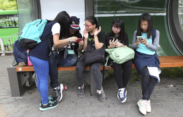 South Korean middle school students use their smartphones at a bus station in Seoul, South Korea, May 15, 2015. (AP)