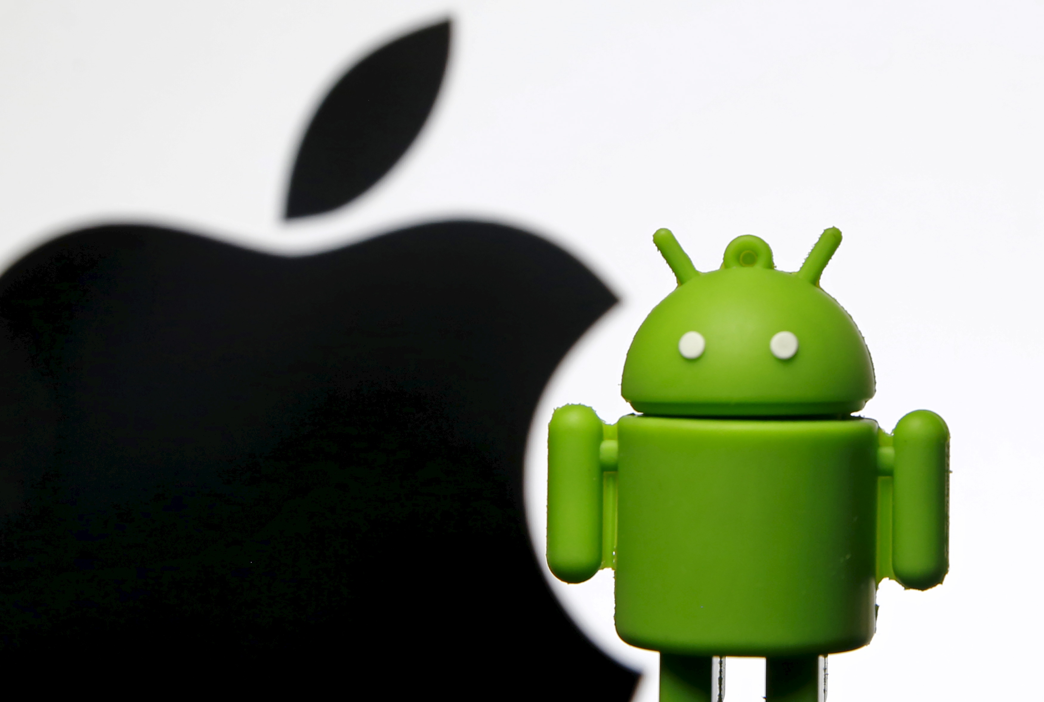 An Android mascot is seen in front of a displayed logo of Apple in this illustration taken in Zenica, Bosnia and Herzegovina, May 5, 2015. (Reuters)