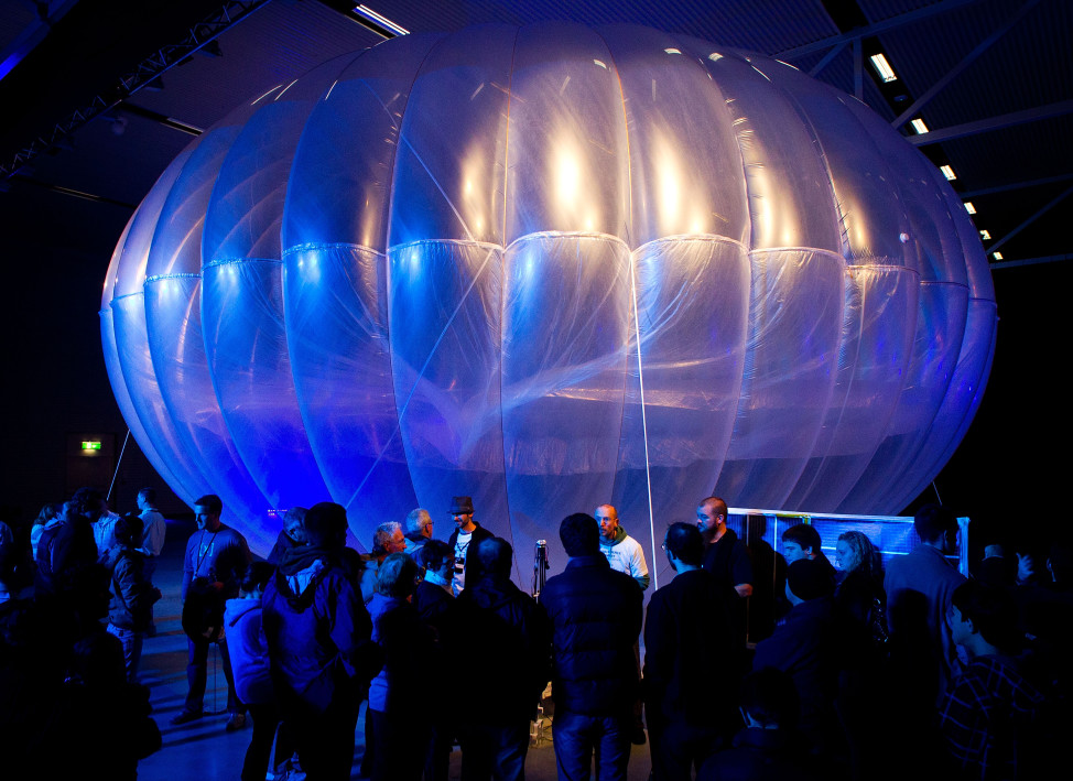 Visitors stand next to a high altitude WiFi internet hub, a Google Project Loon balloon, on display at the Airforce Museum in Christchurch, New Zealand, June 16, 2013.  Google hopes its balloons will bring Internet access to two-thirds of the world's population. (AFP)