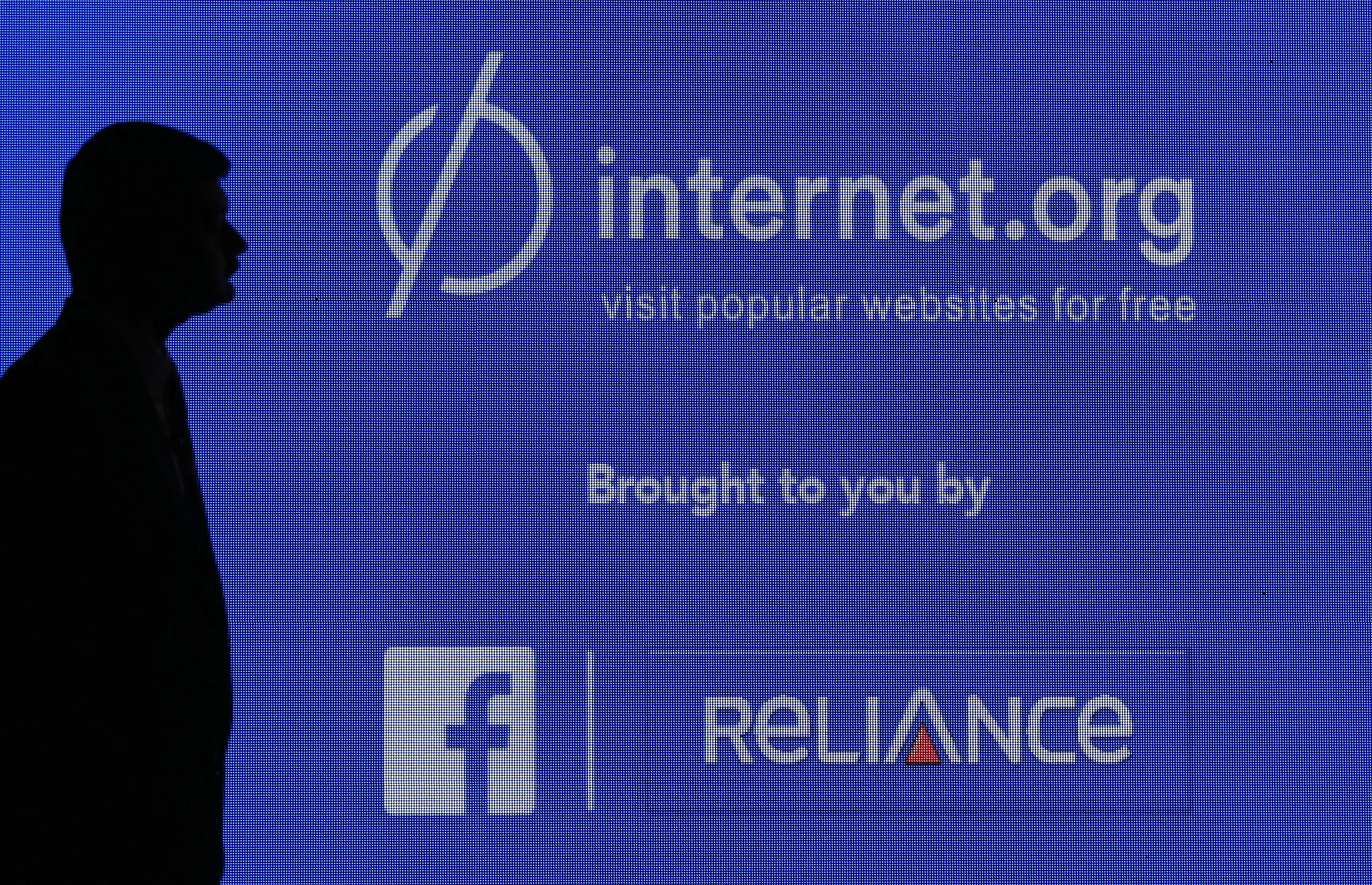 FILE - A staff member stands next to a display screen during a joint news conference by Reliance Communications Ltd. and Facebook Inc. in Mumbai, India, Feb. 10, 2015. (Reuters)
