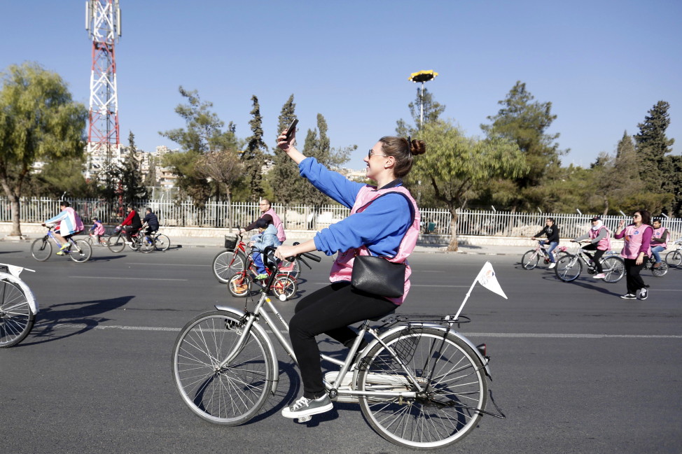 A woman takes a selfie while cycling along a street during a biking tour for charity, in Damascus, Dec. 11, 2015.