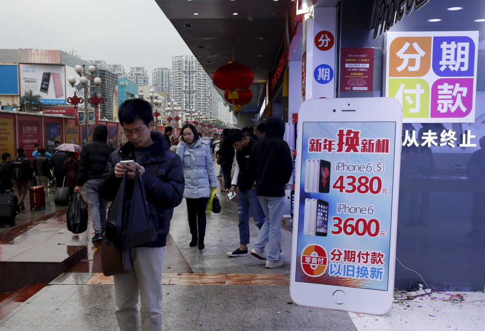 A man checks his smartphone outside a store promoting the Apple iPhone products in the southern Chinese city of Shenzhen, Jan. 26, 2016. (Reuters)