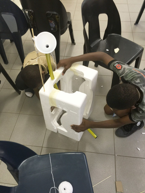 'Design Squad Global' kids at the Phatsimong Youth Center in Gaborone, Botswana build a mouse trap-inspired pill dispenser. The contraption is meant to help kids remember to take their pills in a country with a high prevalence of HIV/AIDS. (WGBH Educational Foundation)
