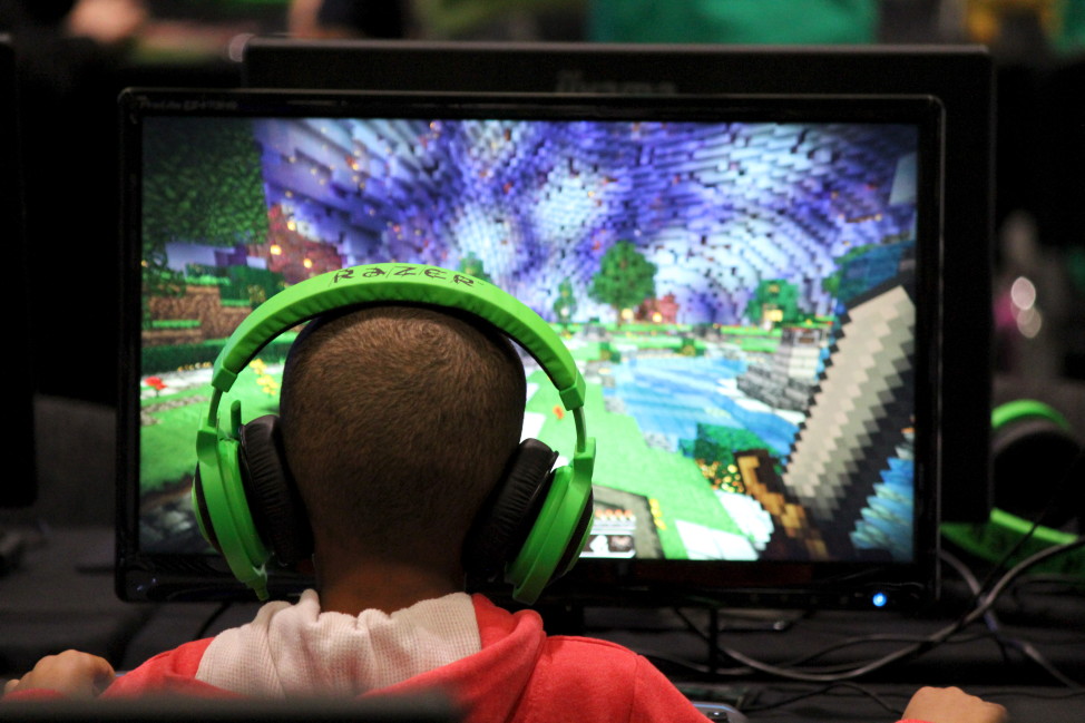 FILE - A child plays the Minecraft video game at the Minecon convention in London, Britain, July 4, 2015. Minecraft is a blocky world that lets players mine for resources and build elaborate structures, among other activities. (Reuters)