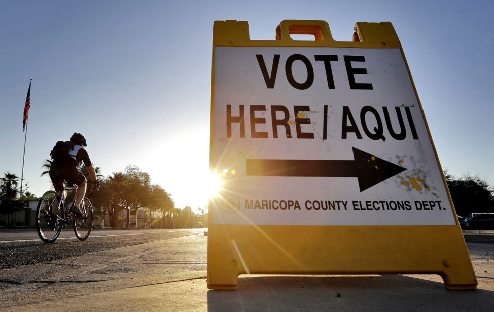 FILE - A cyclist rides past a sign directing voters to a primary election voting station early, in Phoenix. Arizona, Aug. 30, 2016. (AP)