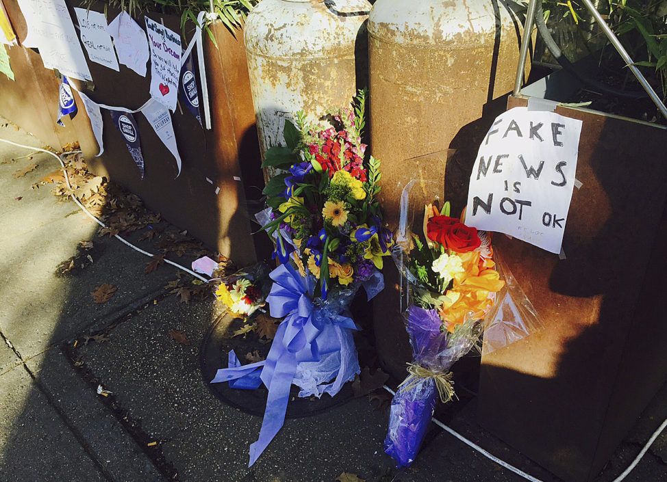 FILE - Flowers and notes left by well-wishers are displayed outside Comet Ping Pong, the pizza restaurant in Washington where an armed man arrived to investigate a fake news story, Dec. 9, 2016. 