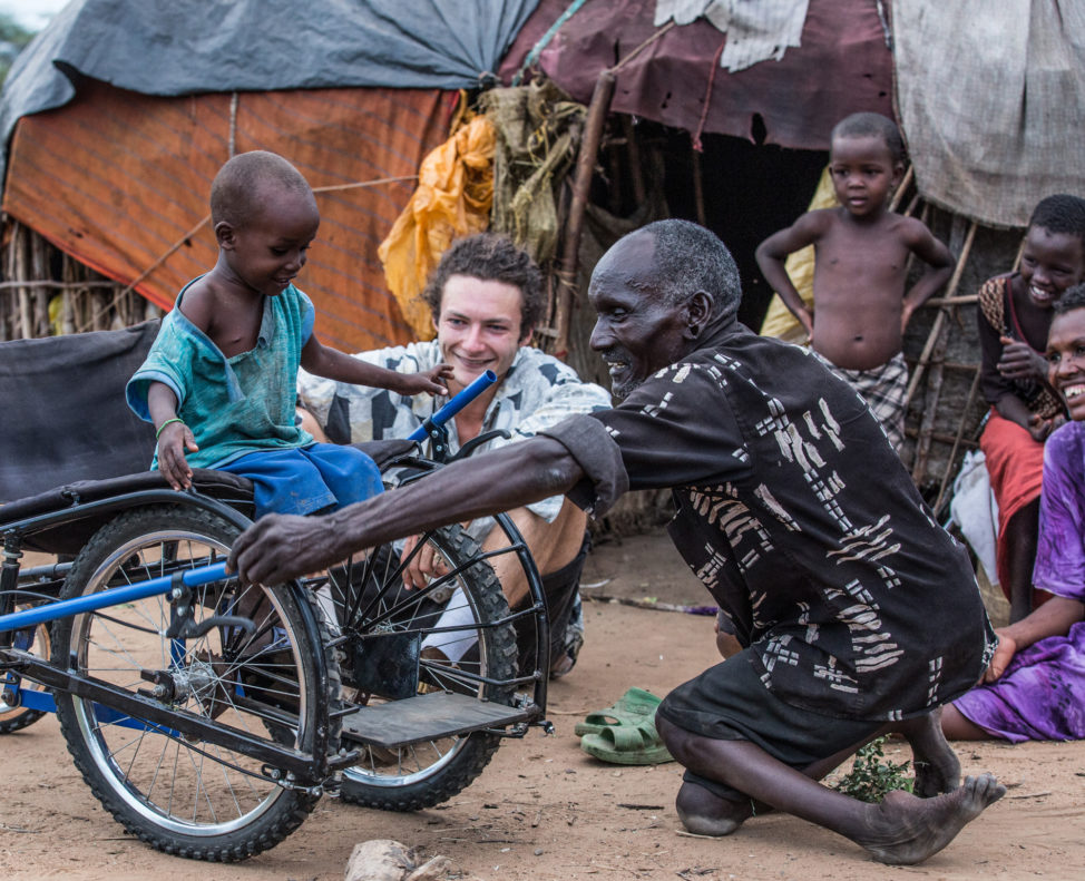 Leu, who was disabled by polio and the inspiration for SafariSeat, shows his son Sabato how to use the wheelchair in Kenya. (Janna Deeble)