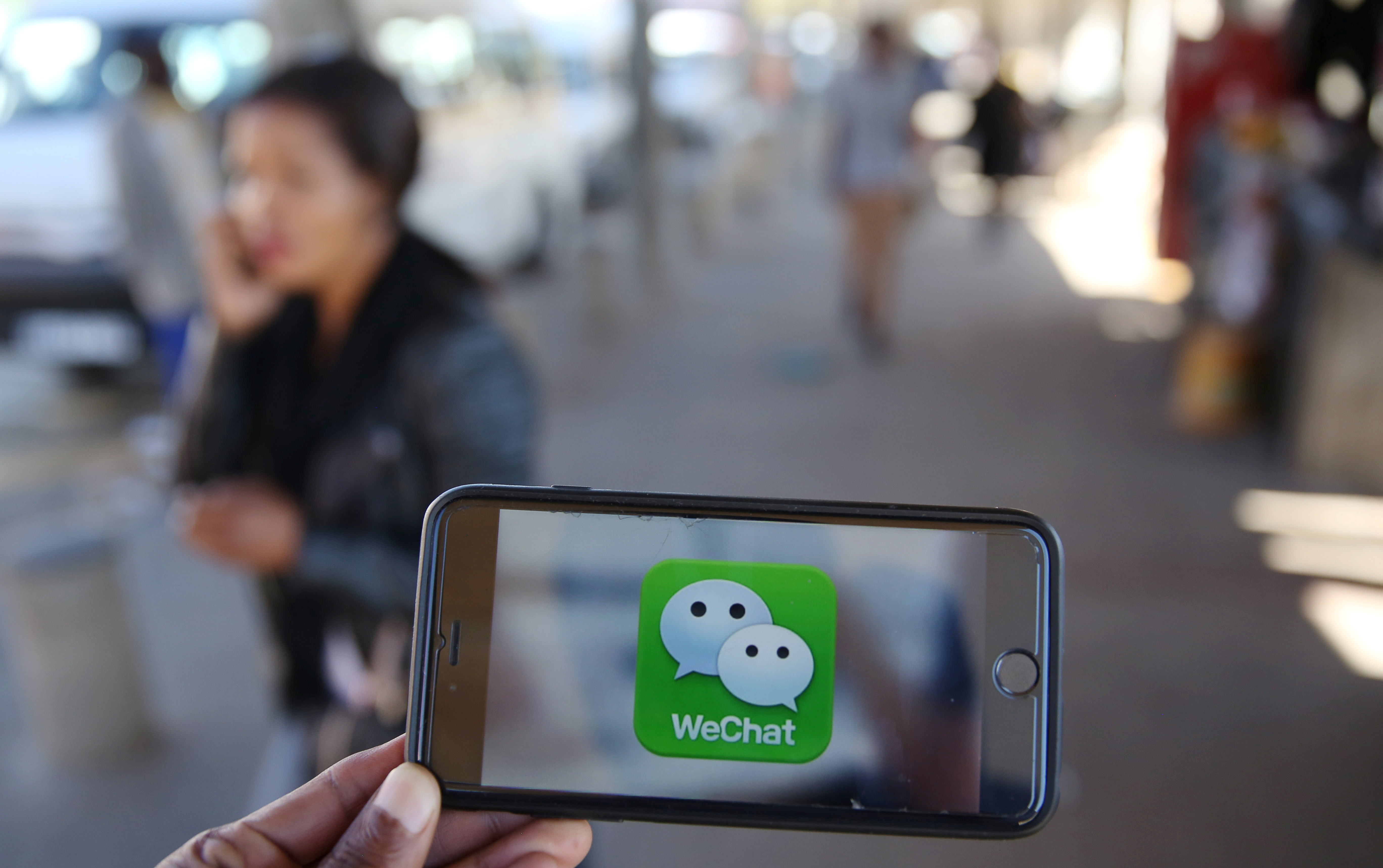 FILE - A WeChat logo is displayed on a mobile phone as a woman talks on her mobile phone in this picture illustration taken July 21, 2016. (Reuters)