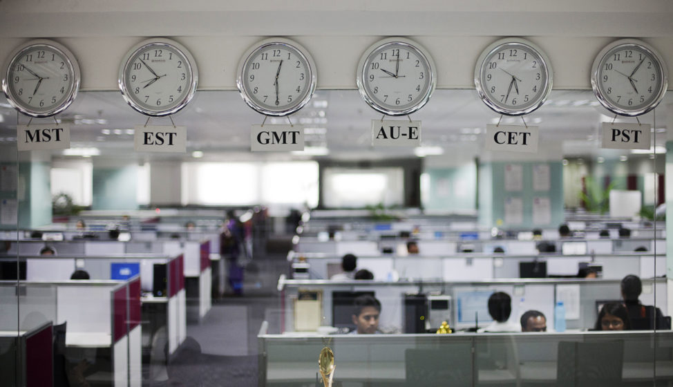 FILE: Workers are pictured beneath clocks displaying time zones in various parts of the world at an outsourcing center in Bangalore.