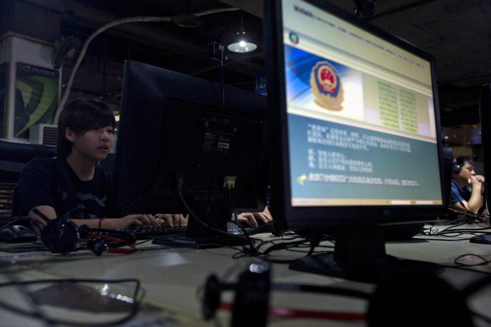 FILE - Computer users sit near a monitor display with a message from the Chinese police on the proper use of the Internet at an Internet cafe in Beijing, China. (AP)