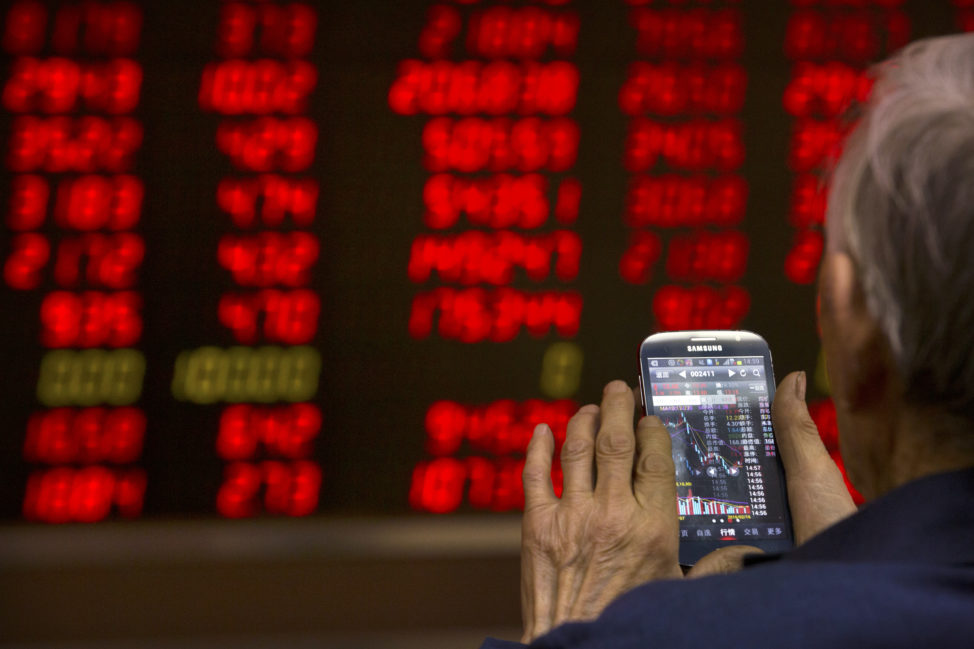 FILE - A Chinese investor uses his smartphone to check stock prices in a brokerage house in Beijing. (AP)