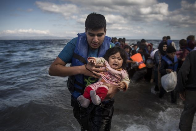 A man holding a baby disembarks from a dinghy after arriving from a Turkish coast to the northeastern Greek island of Lesbos, Sunday, Oct. 25, 2015. The International Office for Migration says Greece over the last week experienced the largest single weekly influx of migrants and refugees this year, at an average of some 9,600 per day. (AP Photo/Santi Palacios)