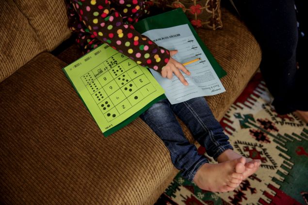 Five-year-old Syrian refugee Leen works on her homework at her new home in Sacramento, California, November 16, 2015. Leen and her family fled violence in Syria three and a half years ago and arrived in Sacramento in September after living in Jordan. Her face is excluded from the photo to protect his identity. To match Feature - FRANCE-SHOOTING/USA-MIGRANTS    REUTERS/Max Whittaker  - RTS7QW8
