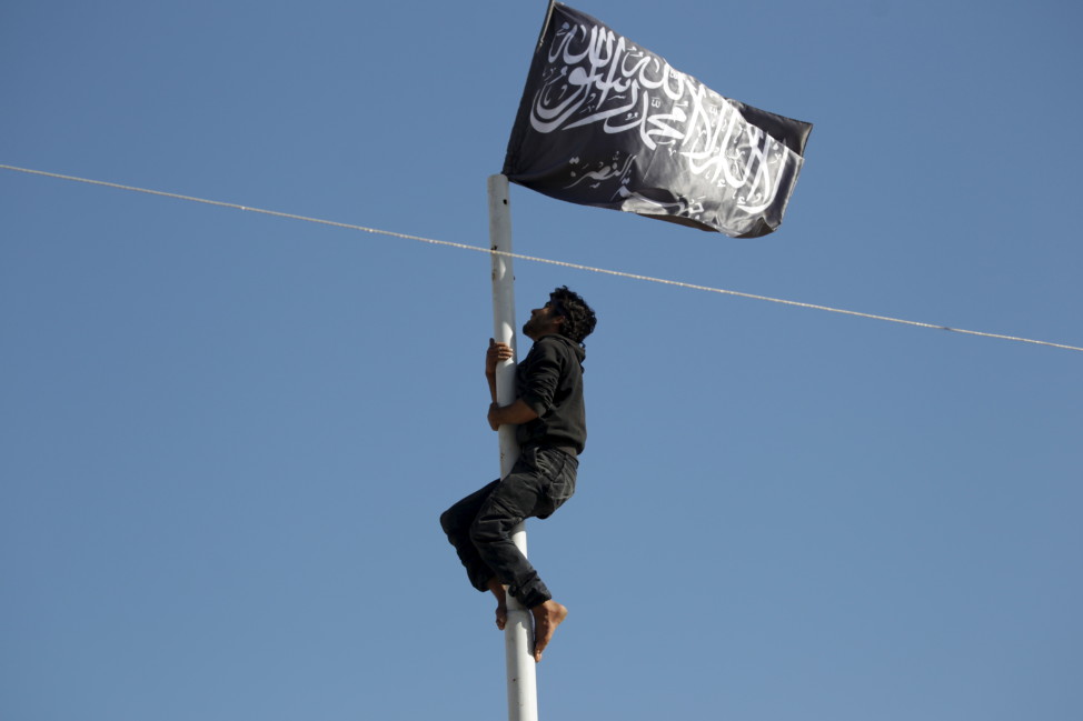 A member of al-Qaida's Nusra Front climbs a pole where the group's flag was raised in Ariha city after a coalition of insurgent groups seized the area in Syria's Idlib province on May 29, 2015. (Reuters)