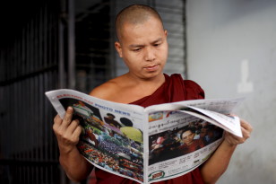 A Buddhist monk reads a newspaper on a street in Yangon on Nov, 9, 2015. (Reuters)