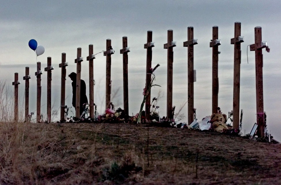This April 28, 1999 file photo shows a woman standing among 15 crosses posted on a hill above Columbine High School in Littleton, Colo., in remembrance of the 15 people who died during a school shooting on April 20, 1999.  (AP)