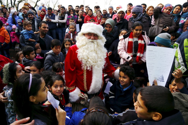 Migrant children surround a volunteer dressed as Father Christmas during a Christmas gathering organized by local relief organization "Die Johanniter" at the refugee camp in Hanau, Germany, December 24, 2015. (REUTERS)