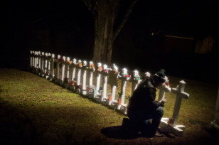 Frank Kulick adjusts a display of wooden crosses and a Jewish Star of David representing the victims of the Sandy Hook Elementary School shooting, on his front lawn on Dec. 17, 2012, in Newtown, Conn. (AP) 